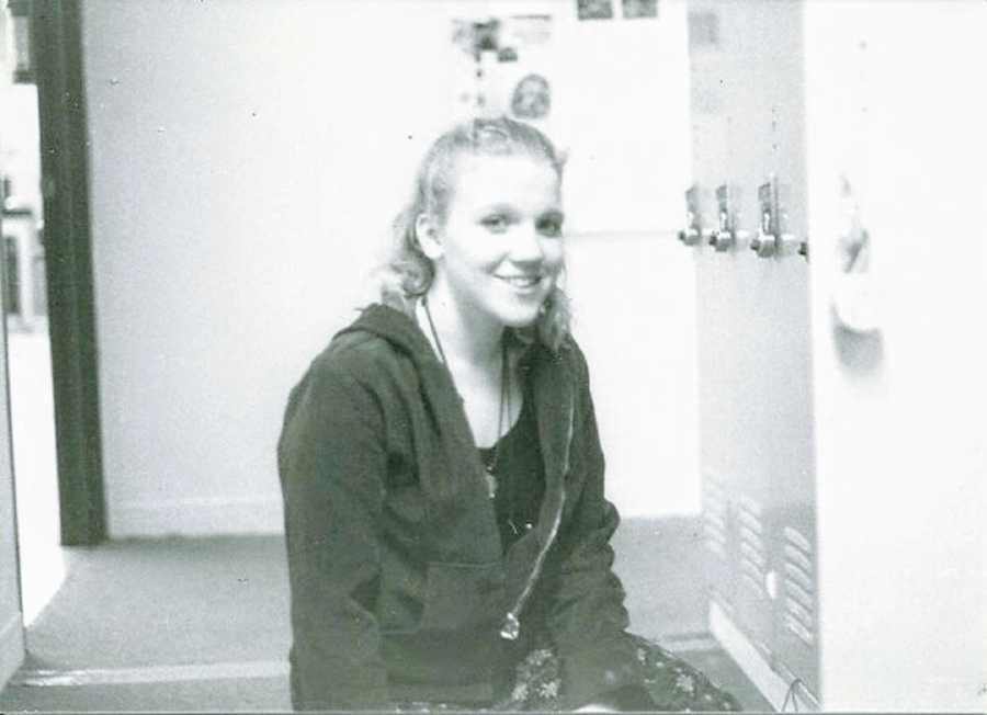 A young woman sits in a locker room alone