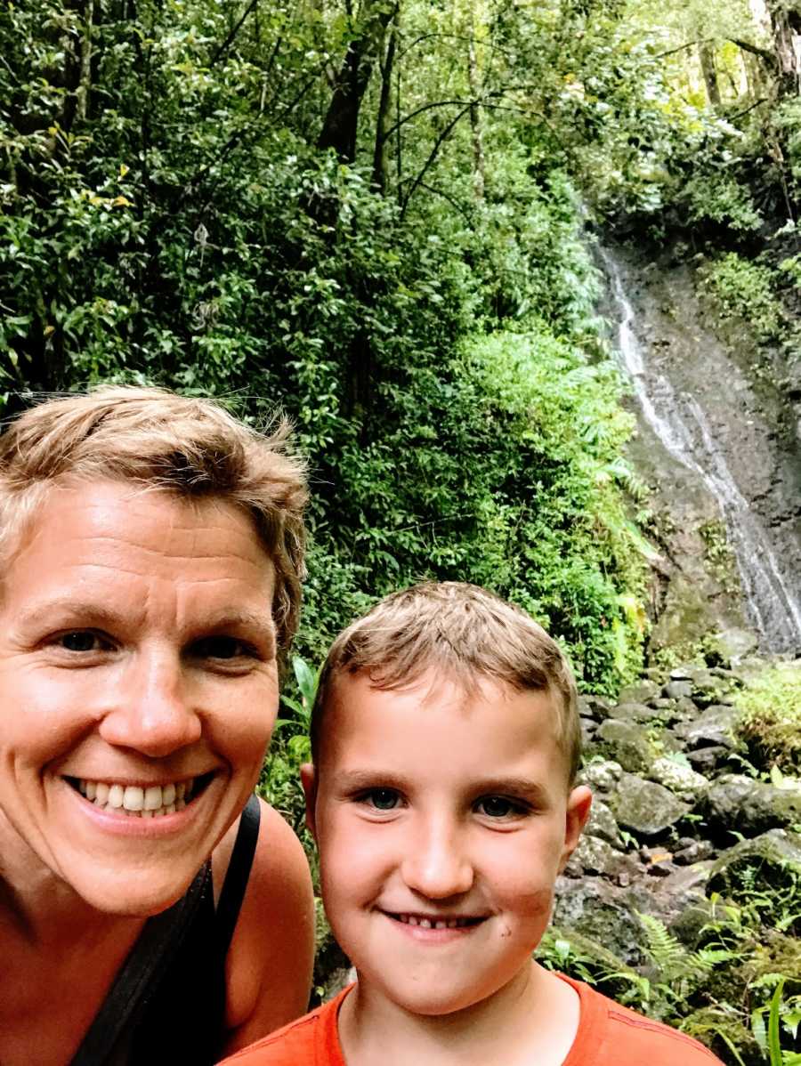 An autistic mom and her son in the woods by a waterfall