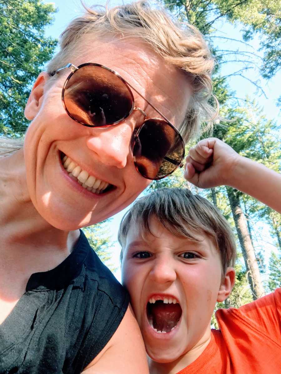 A mom in the woods with her autistic son, whose mouth is open