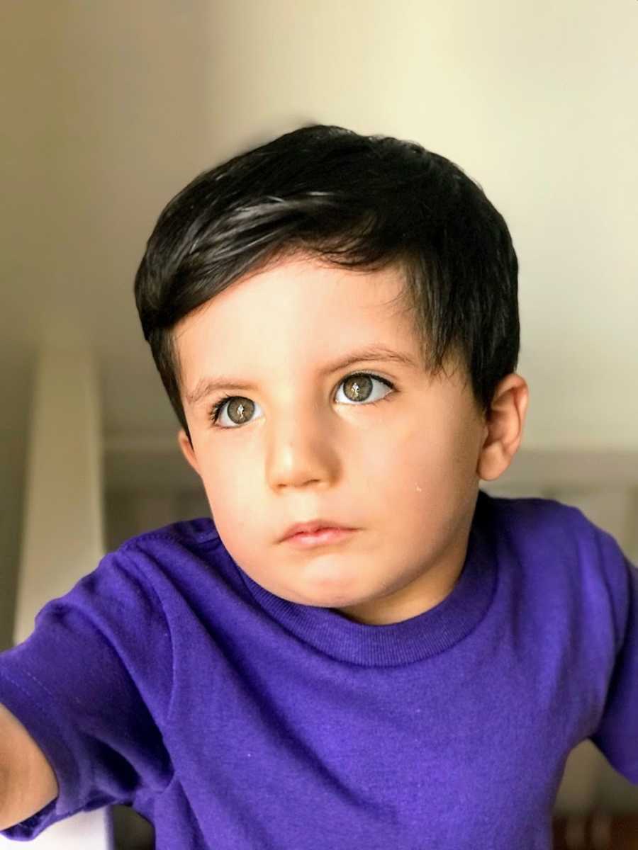 Toddler boy wearing purple shirt looking off into distance