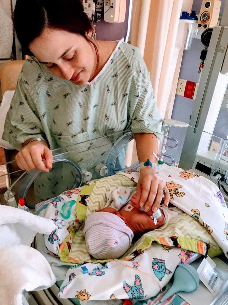 New mom touching newborn son who is hooked up to machines in hospital