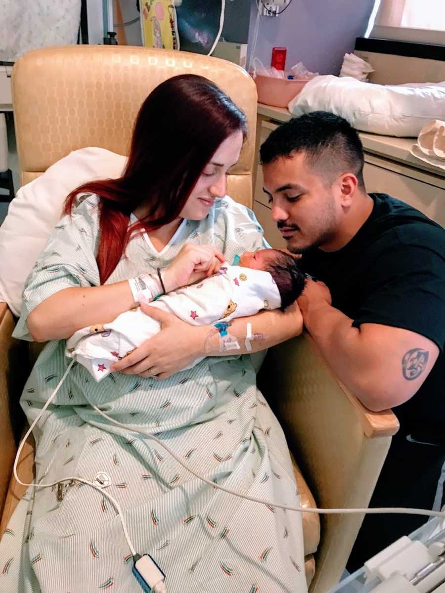 New parents holding baby son in hospital