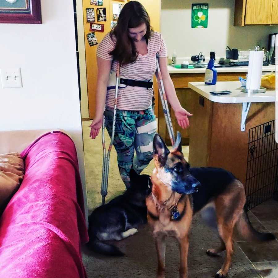 Woman standing with dogs using crutches