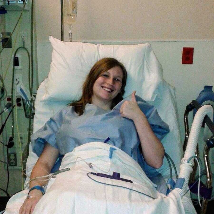 Young woman in hospital bed after surgery giving thumbs up