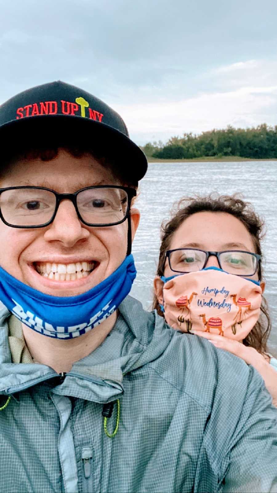 A comedian and his wife in masks by the water