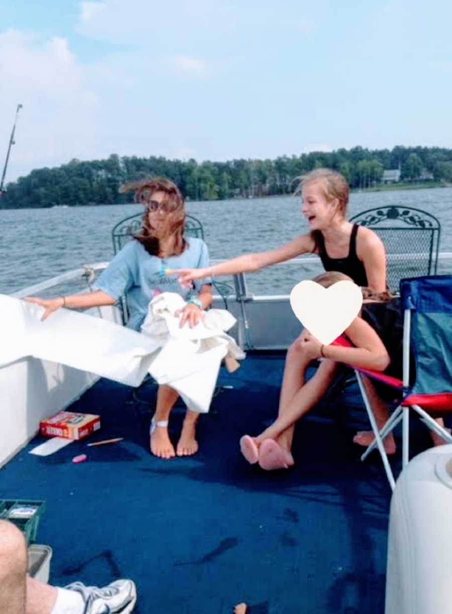 Three young women sit together on a boat