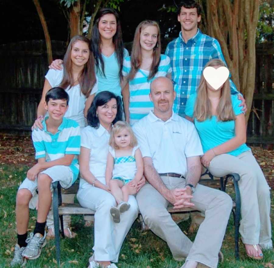 A family with four adopted children sits together wearing blue and white