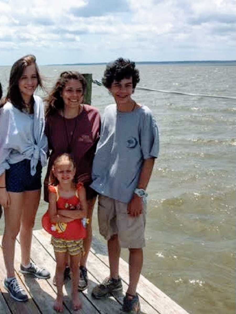 A young woman stands with three of her adopted siblings