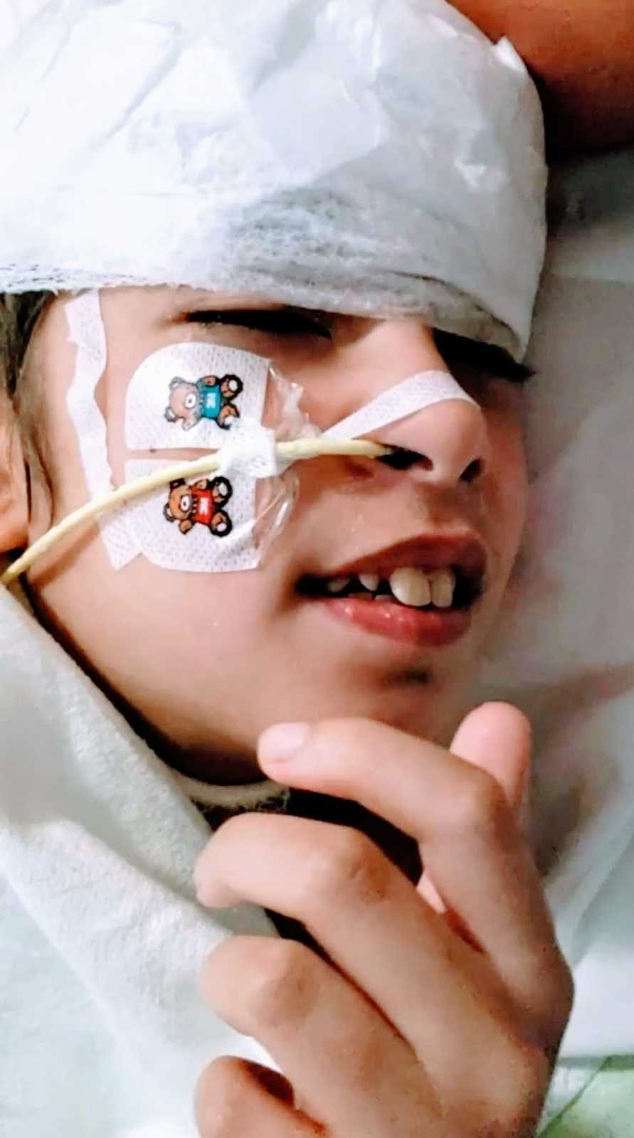 A boy with a rare chromosome disorder lies in a hospital bed hooked up to wires