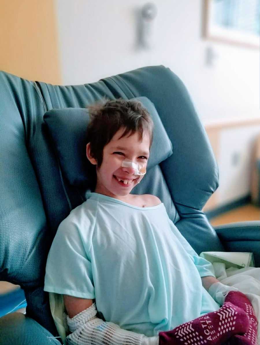 A boy with a rare chromosome disorder smiling and sitting in a chair at a hospital