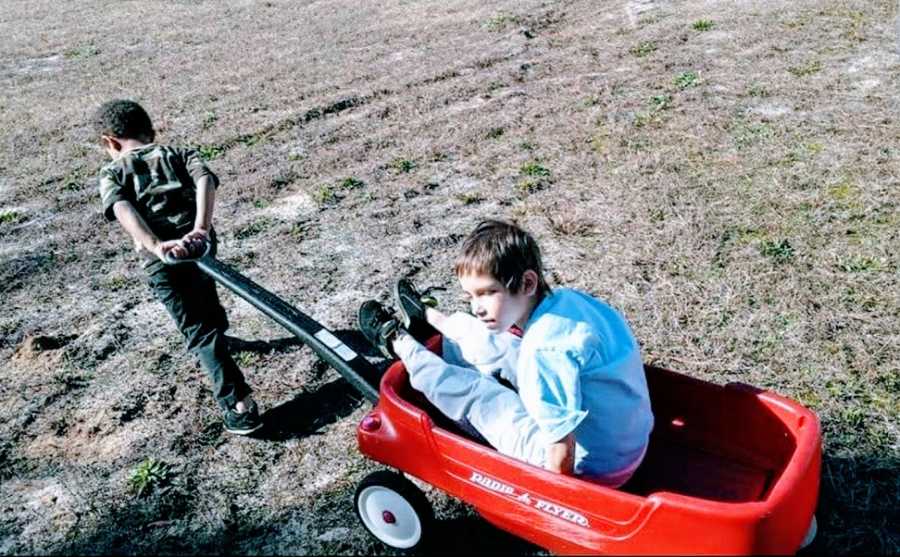 A boy with a rare chromosome disorder is pulled by his brother in a wagon