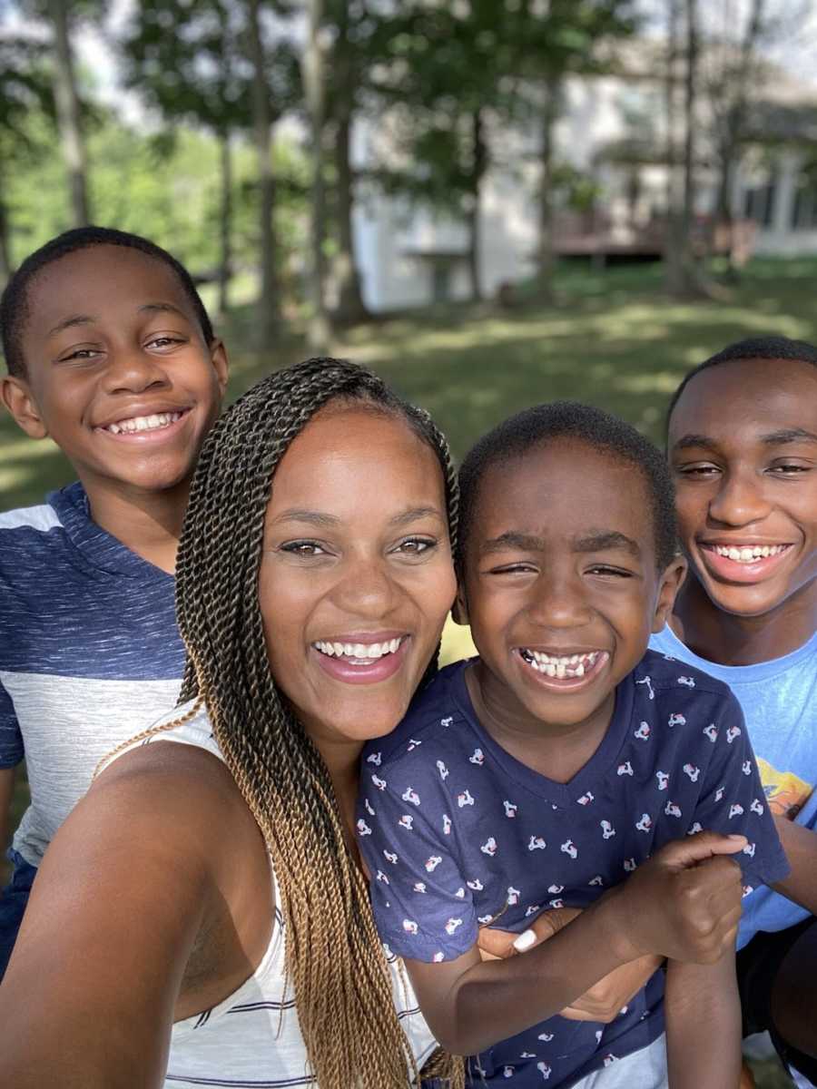 Mom standing outside with three sons smiling