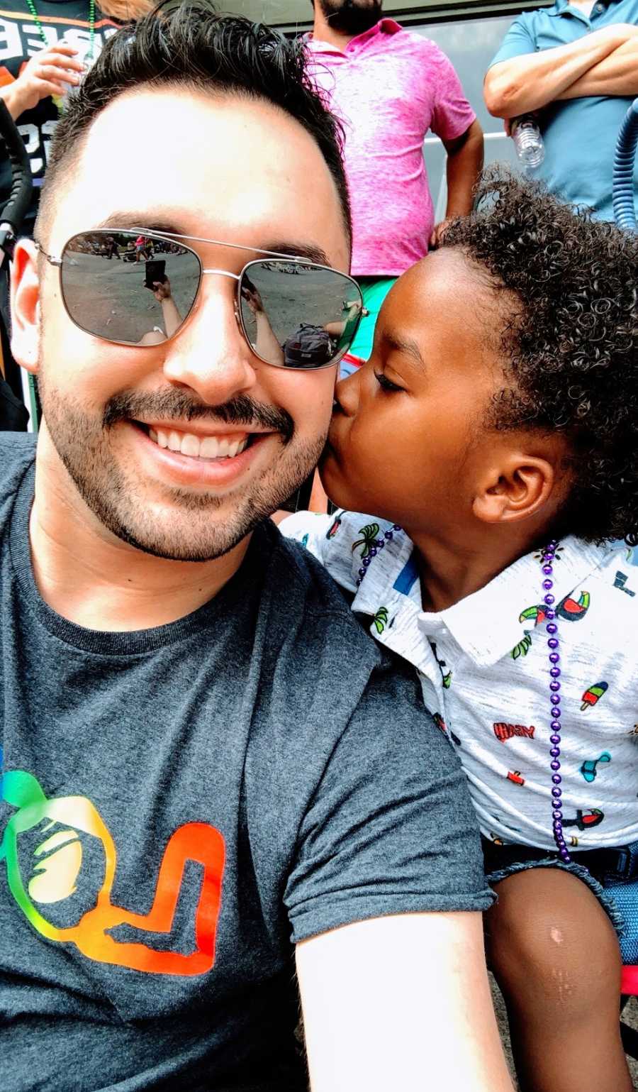 A toddler kisses his adoptive father on the cheek