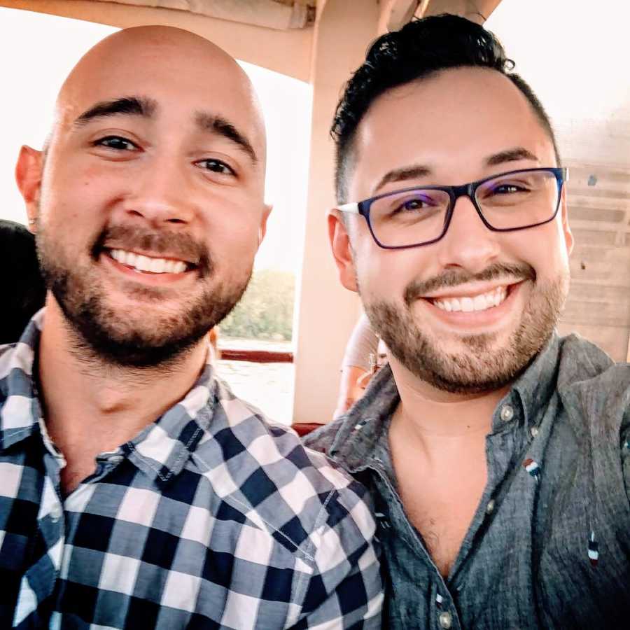 A pair of gay men, one in a checkered shirt and the other wearing glasses