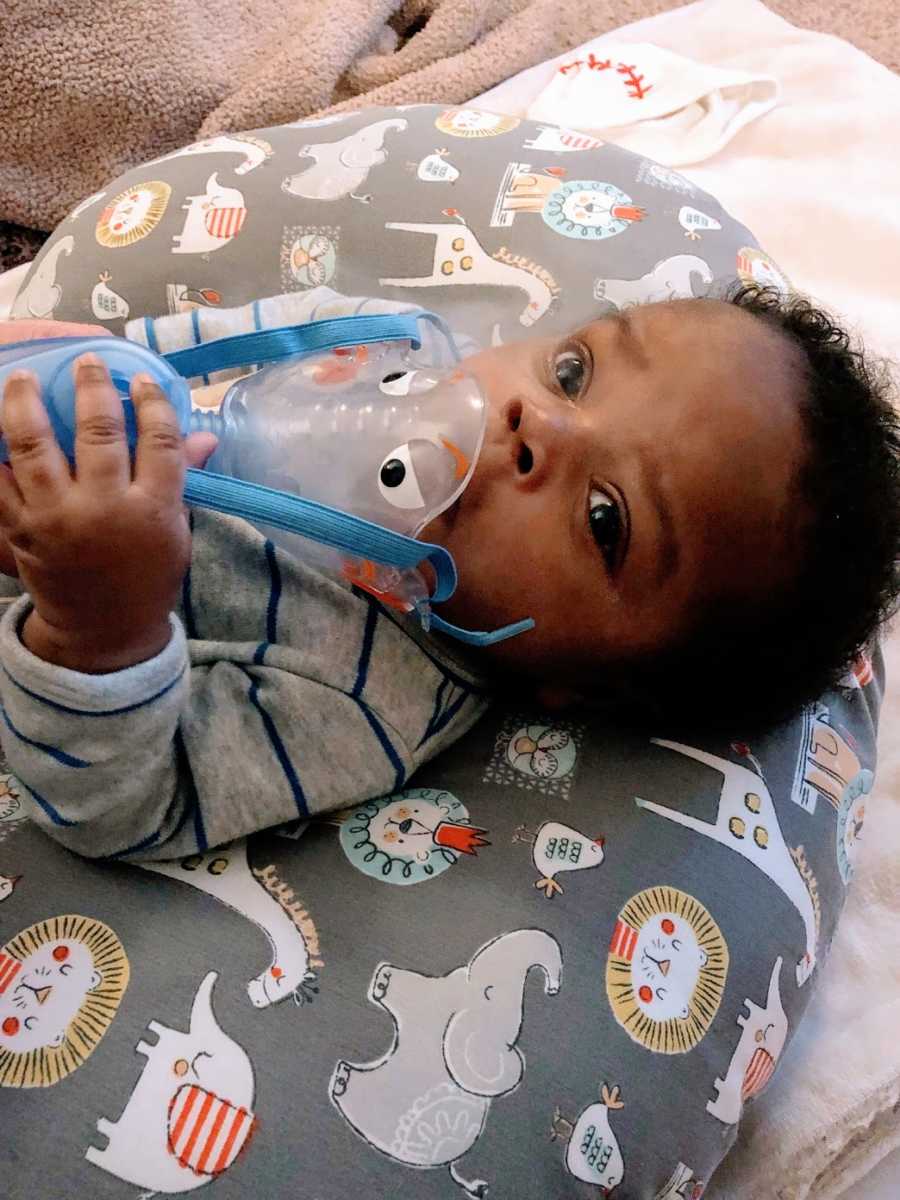 A baby with asthma breathes into an inhaler