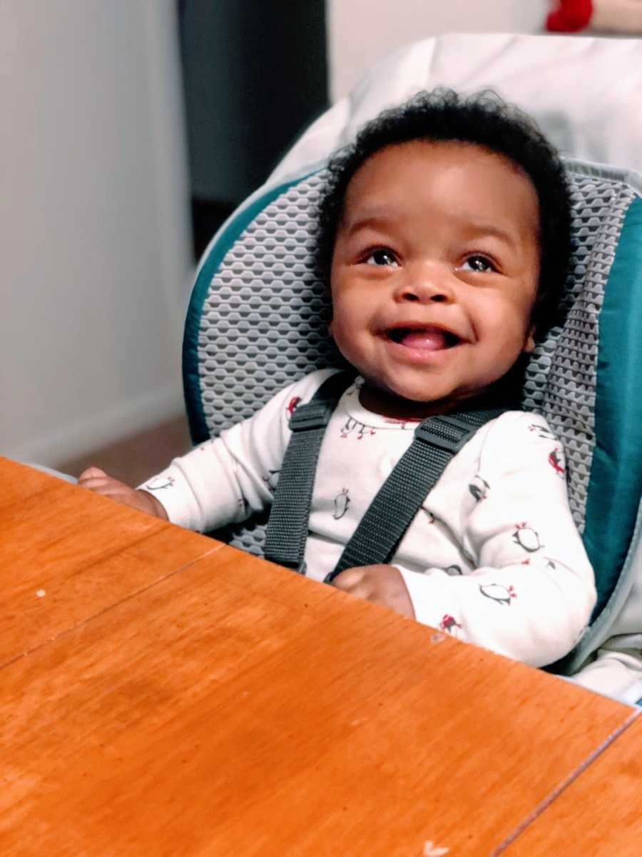 A baby strapped into a highchair at a table