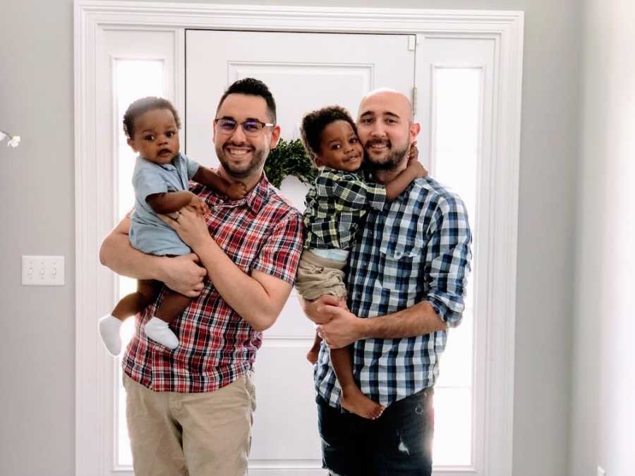 Gay fathers hold up their adoptive sons