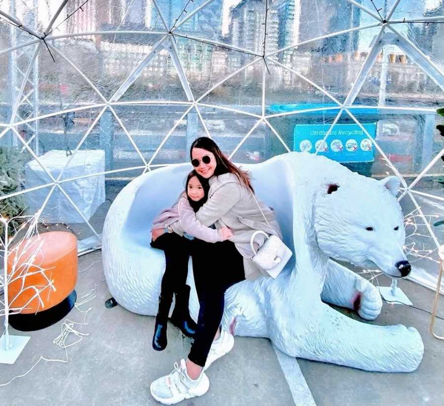 A single mother holds her daughter in a polar bear chair