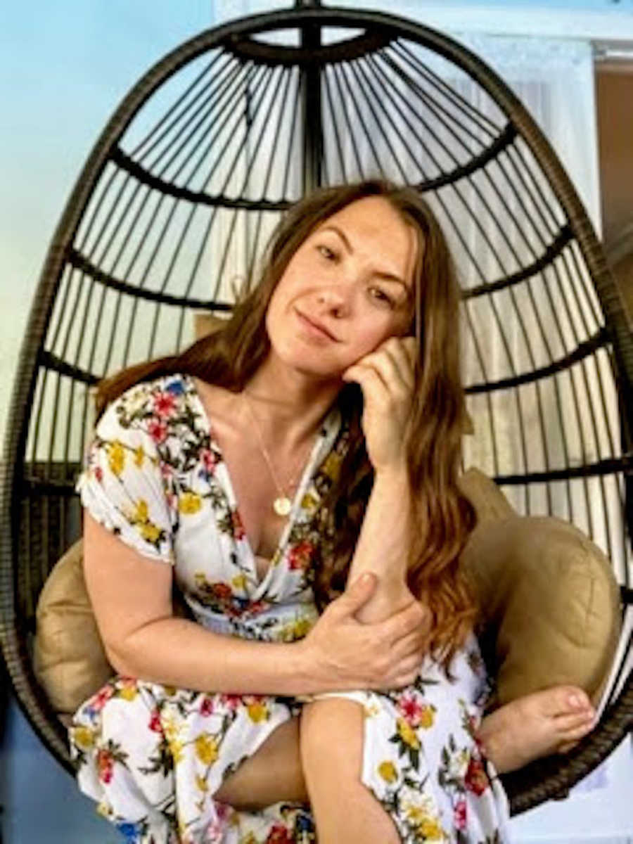 Woman sitting in basket chair with head resting on hand