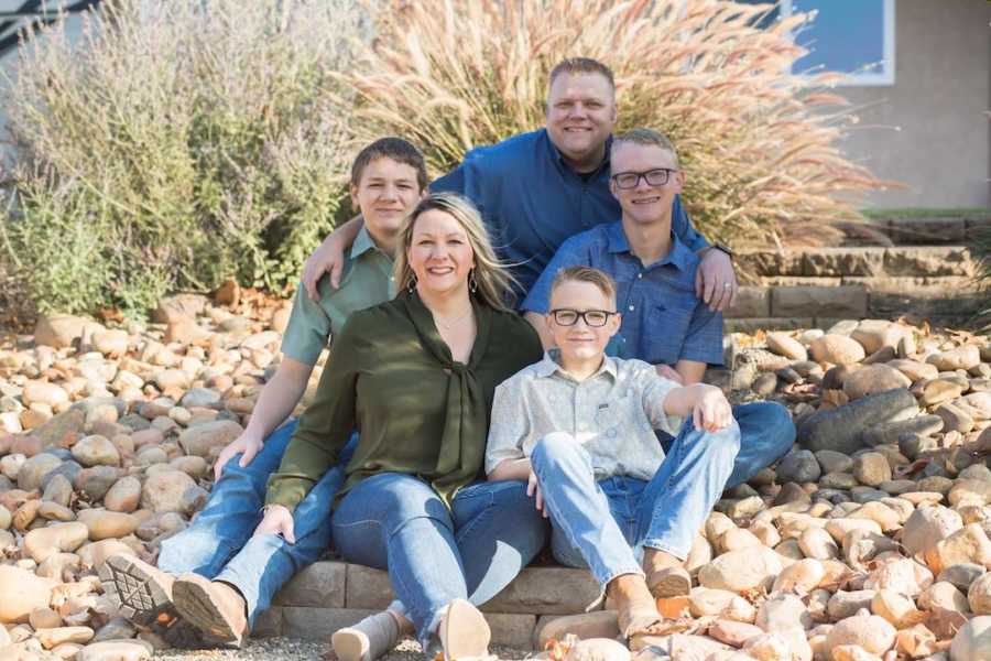 Family of five sitting outside smiling for family photo