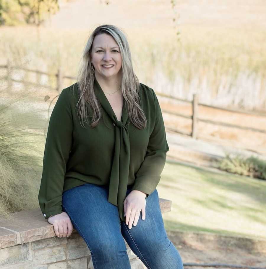 Woman sitting outside on farm smiling wearing green shirt
