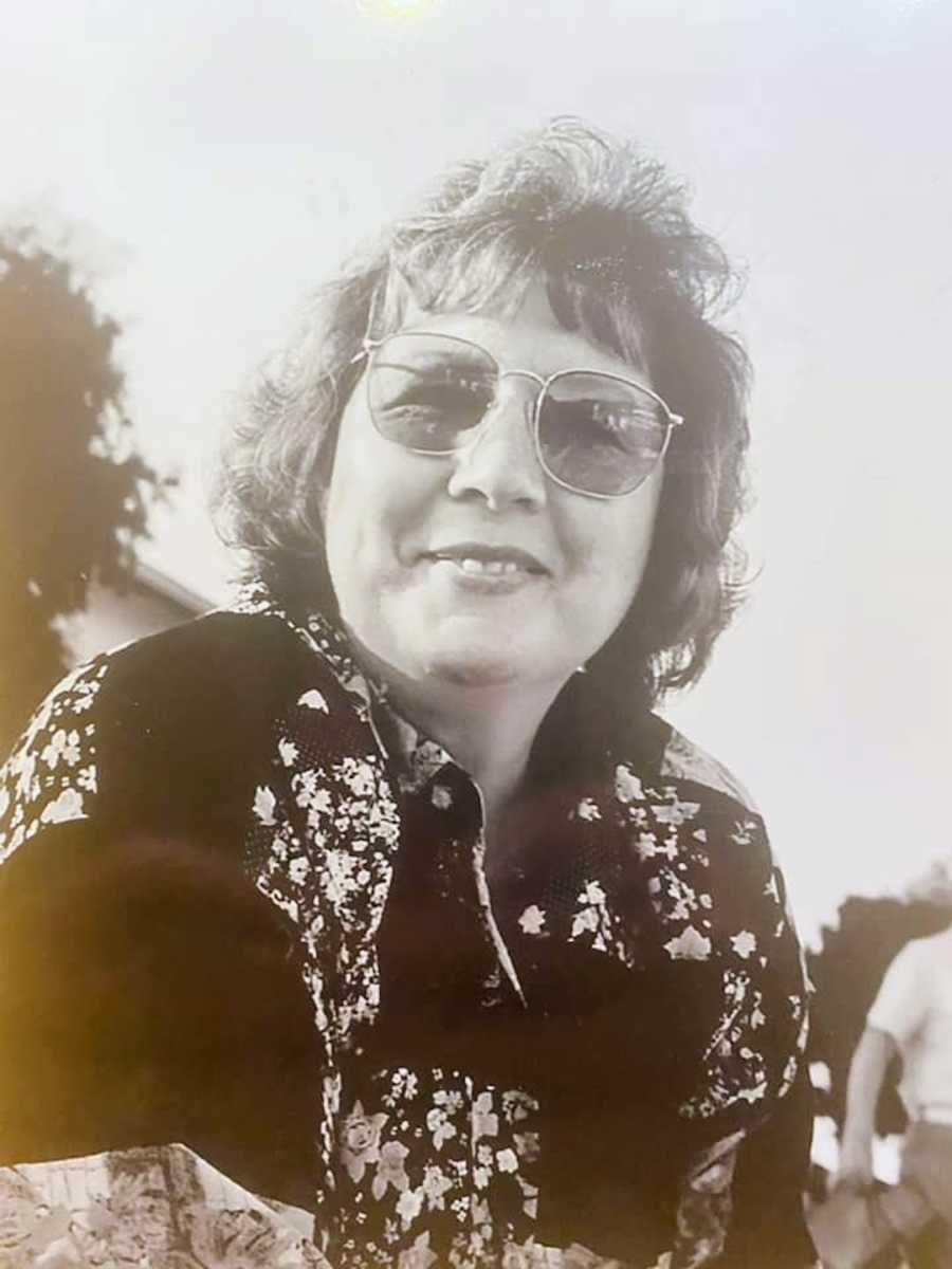 Black and white photo of woman sitting outside wearing sunglasses