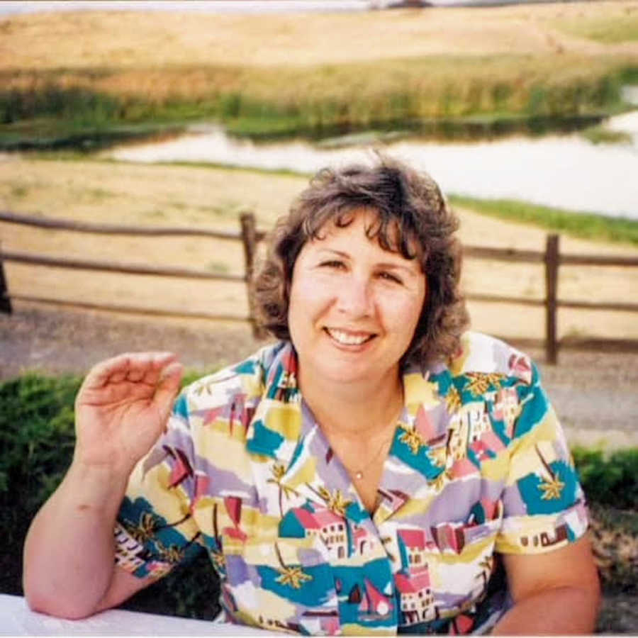 Mother waving to camera sitting outside and smiling