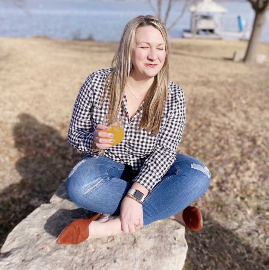 Woman sitting outside on ground holding drink