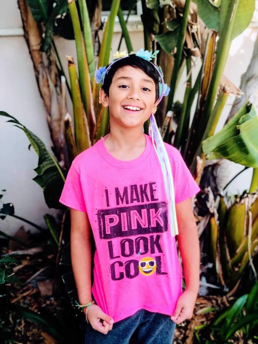 A boy wears a pink shirt and a flowery headband