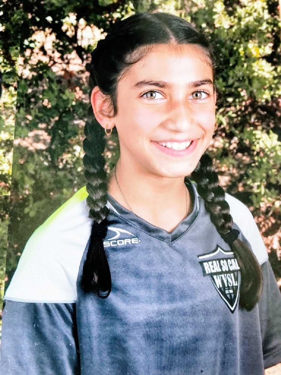 A girl wears a soccer jersey and French braids for picture day
