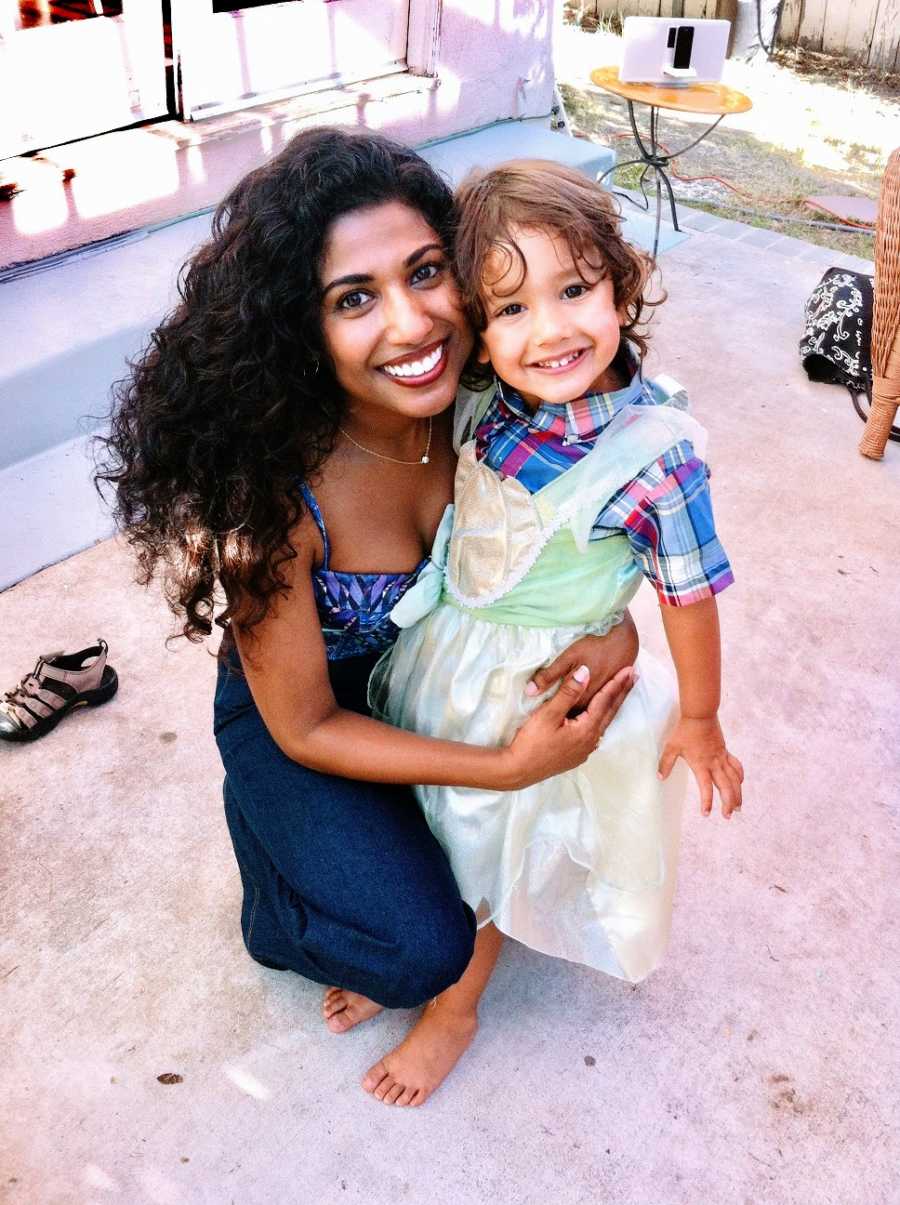 A mom holds her son who is wearing a green princess dress