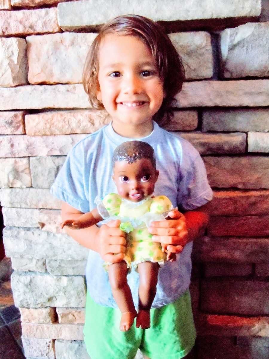 A boy smiles while holding his favorite doll