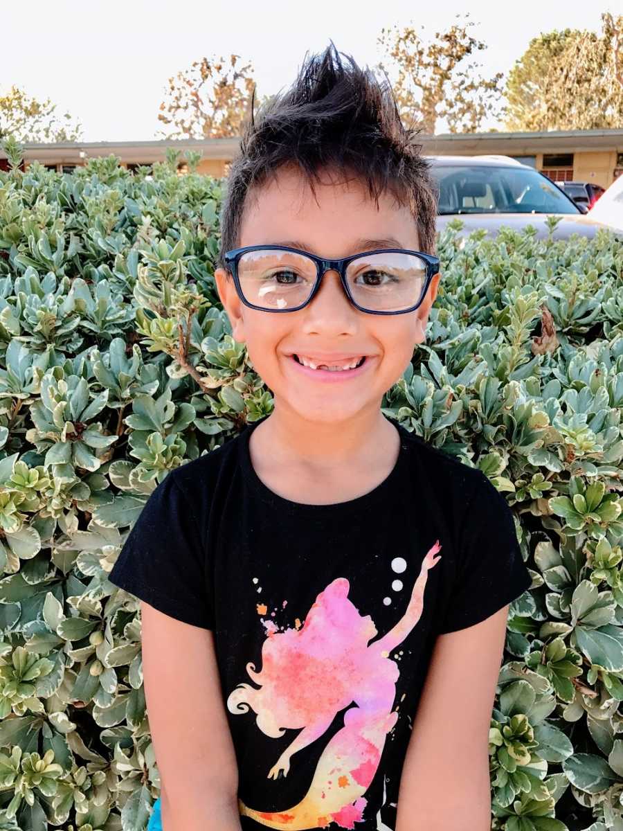 A boy wearing glasses and a pink mermaid shirt