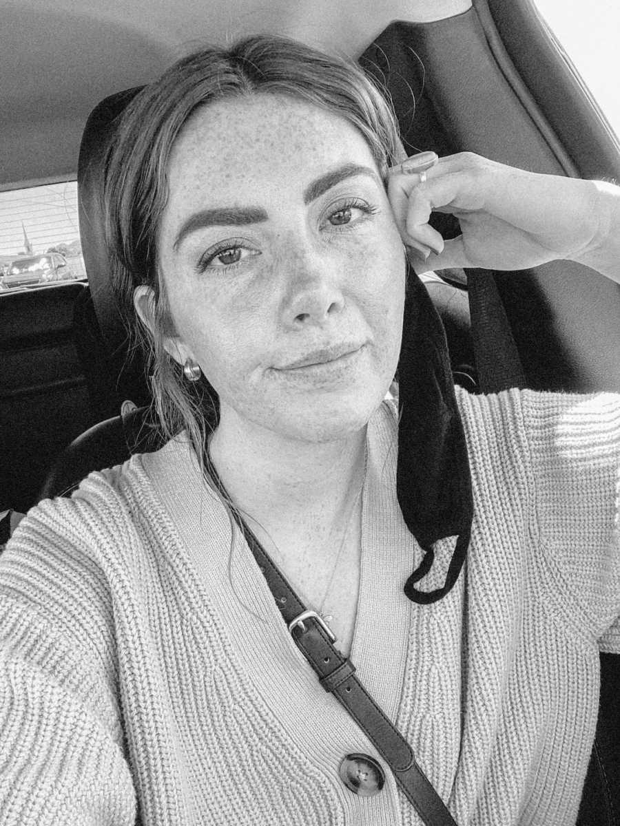 Black and white photo of woman wearing mask staring into camera