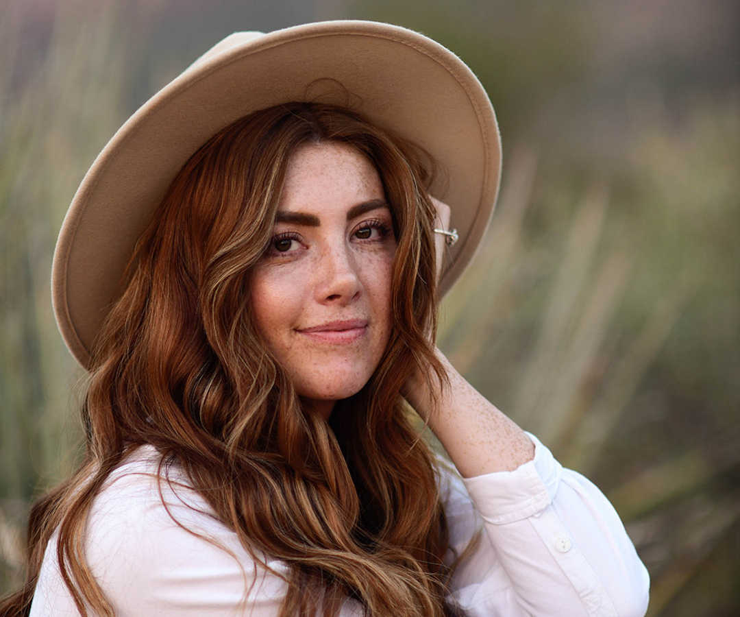 Woman wearing hat posing outside smiling