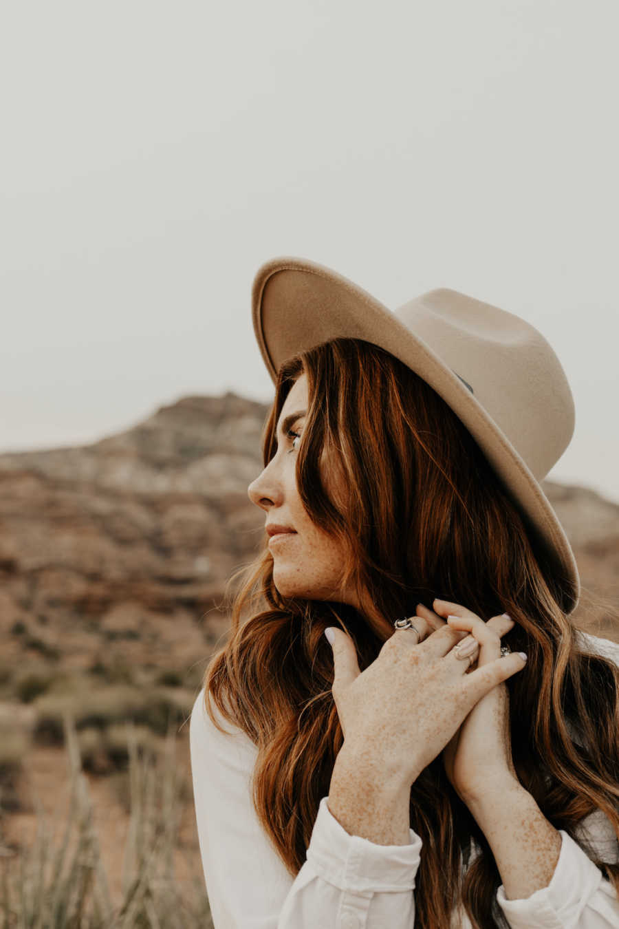 Woman wearing hat standing outside looking off into the distance