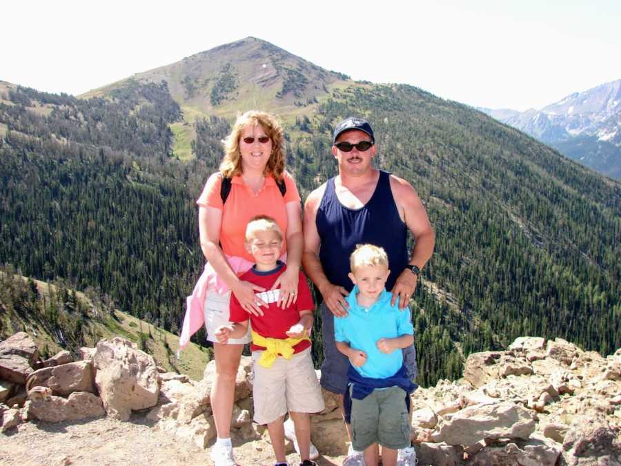 Family of four standing in front of mountain with trees