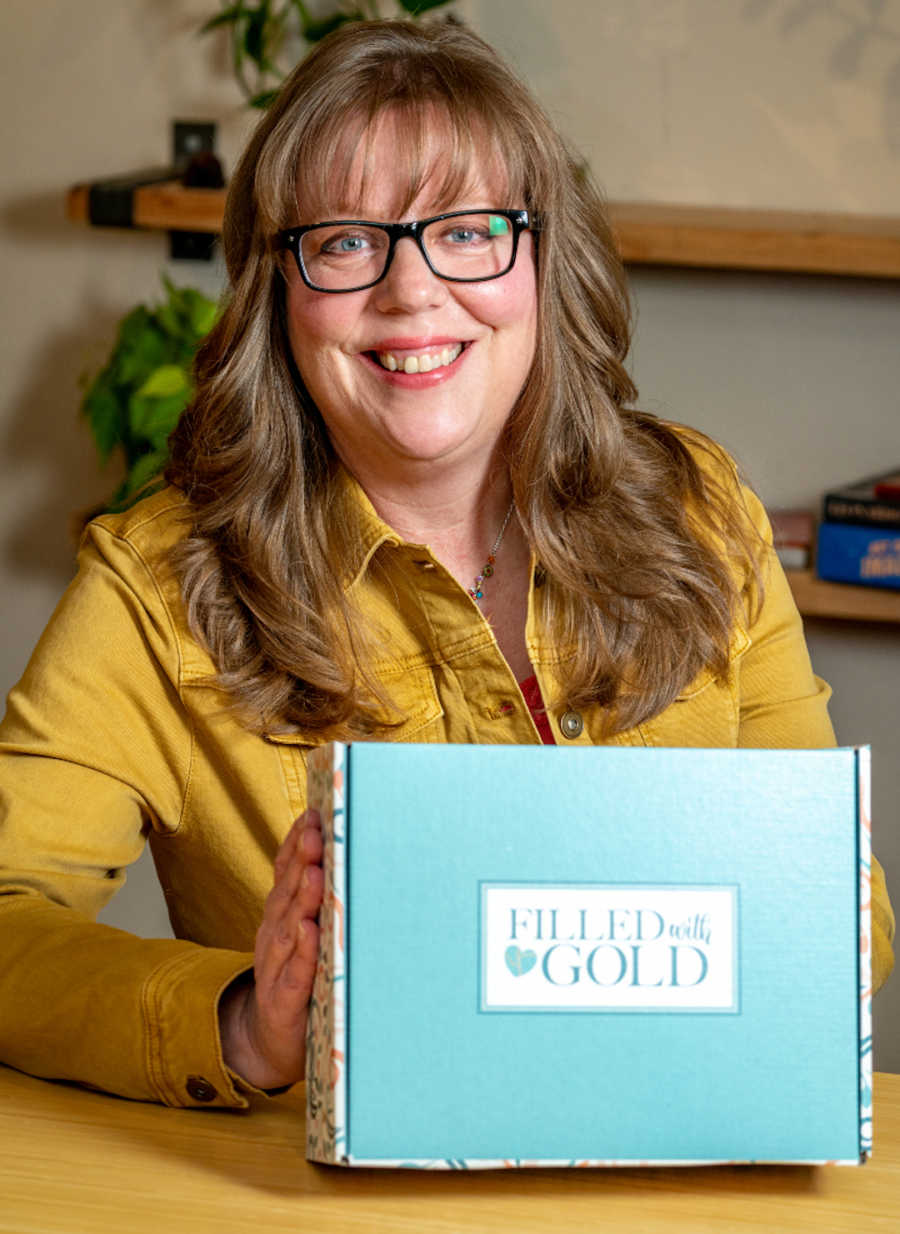 Woman holding self-care subscription box and smiling