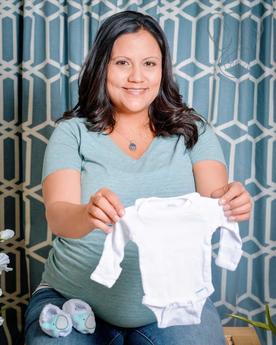 An expectant single mother by choice holds a white infant shirt