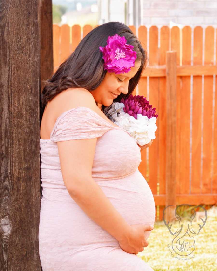 A pregnant single mother by choice holds her belly wearing a pink dress