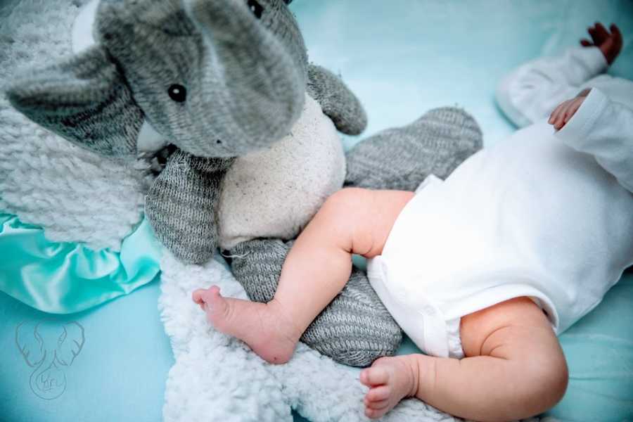 A baby girl's feet next to her deceased brother's toy elephant