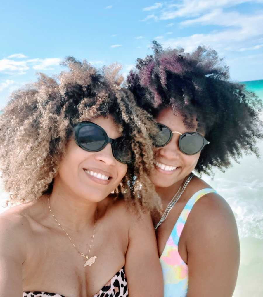 A lesbian woman and her wife wearing sunglasses at the beach