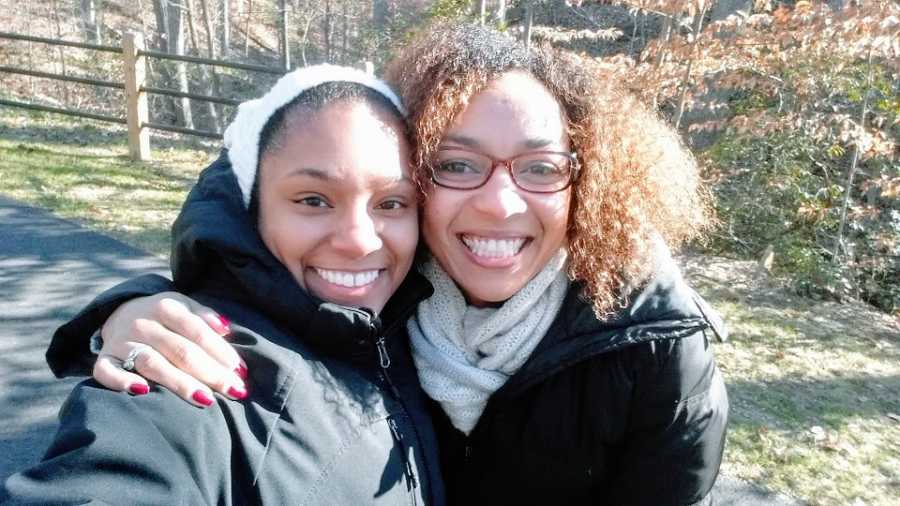 A woman with her arm around her wife, both wearing coats