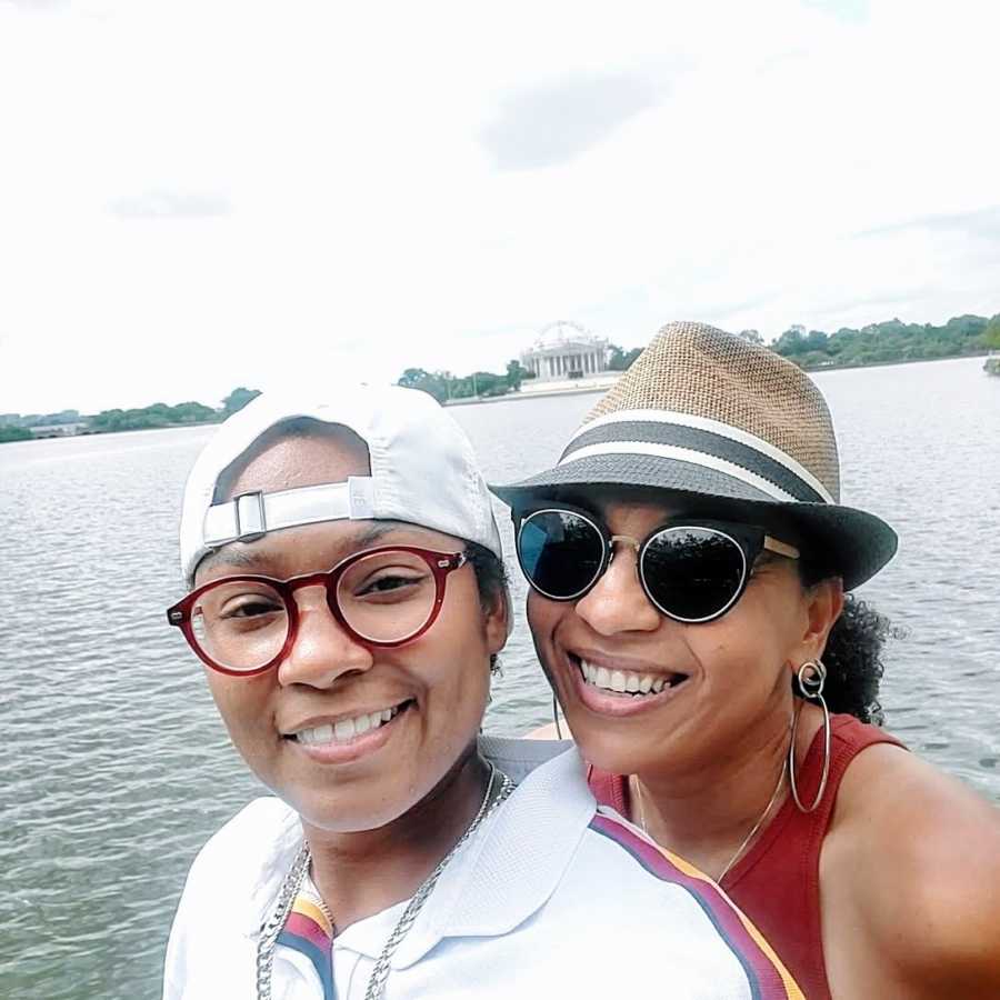 A lesbian woman and her wife by the water wearing hats