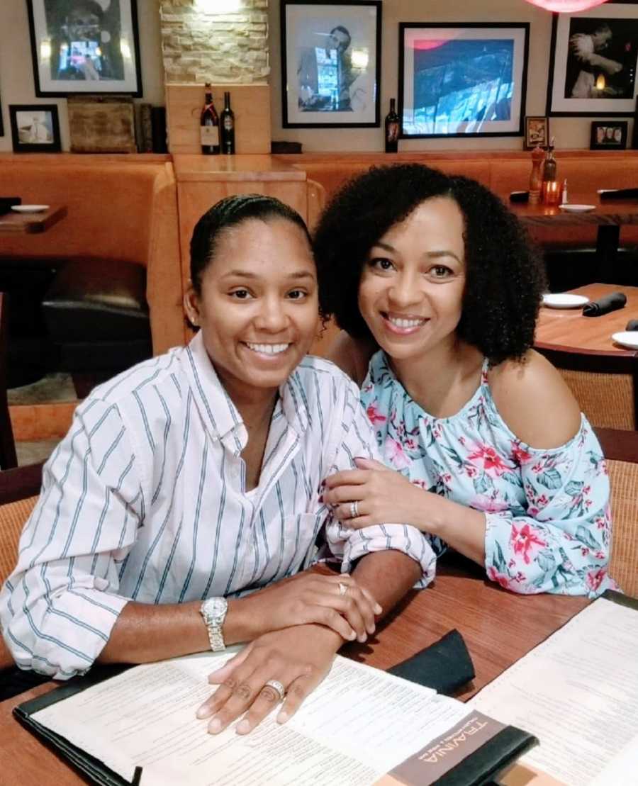 A woman and her wife sit together at a table in a restaurant