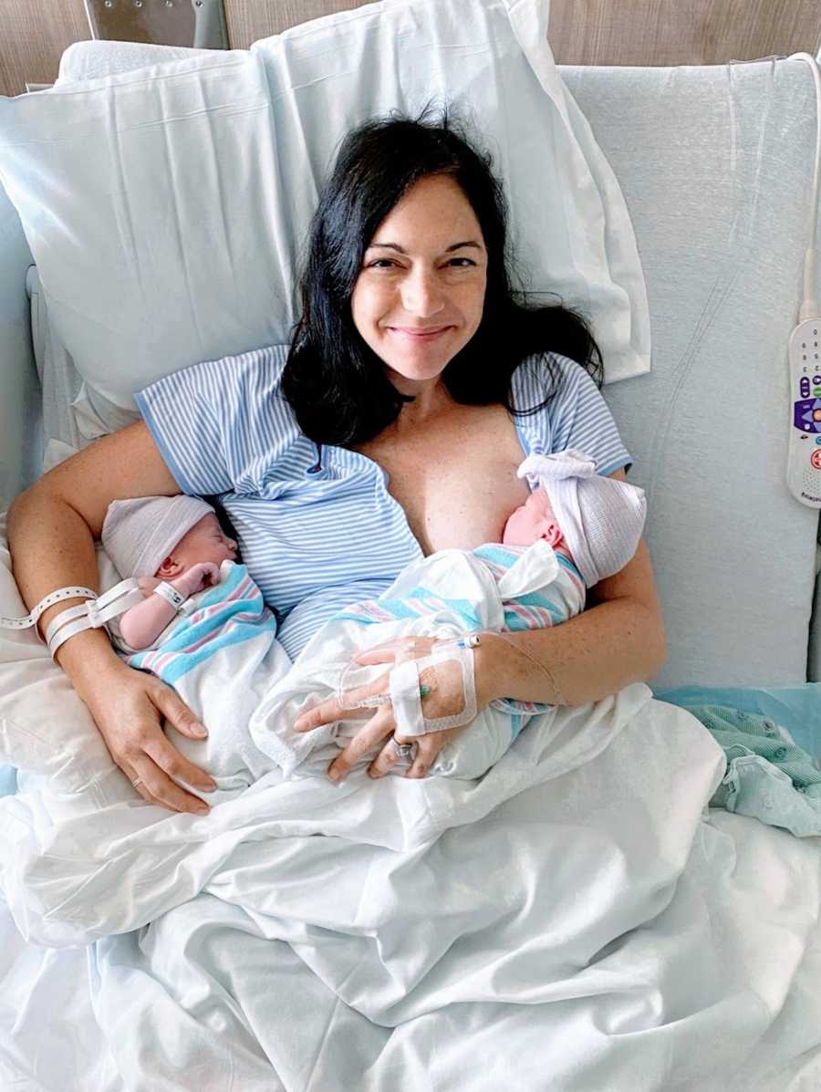 妈妈抱着新出生的双胞胎在医院病床上