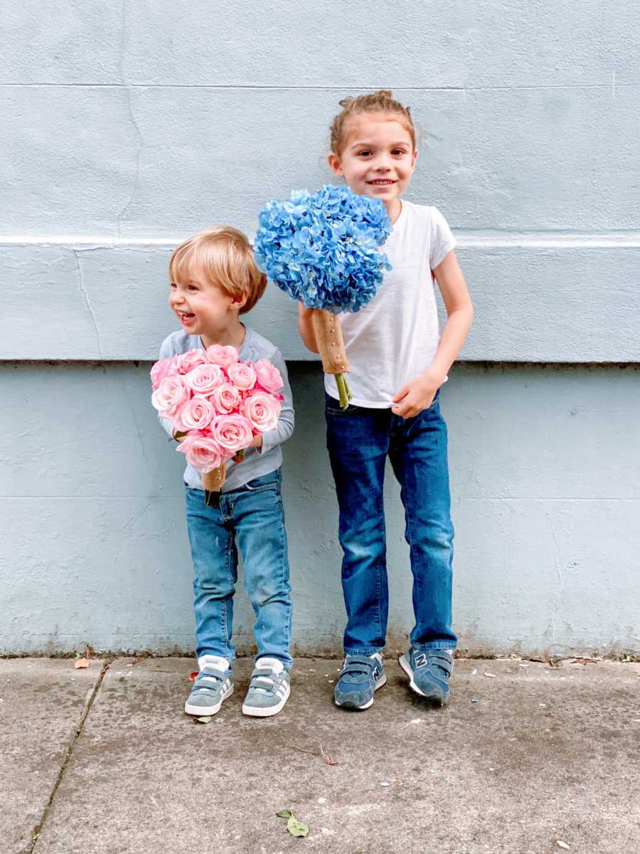 Two brothers holding a pink and a blue bouquet of flowers