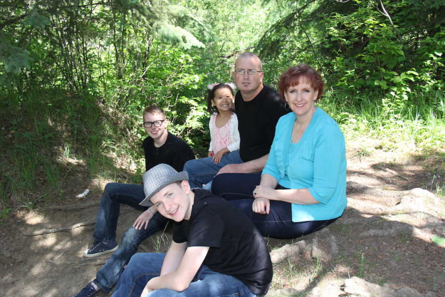 Family of five sitting outside in woods
