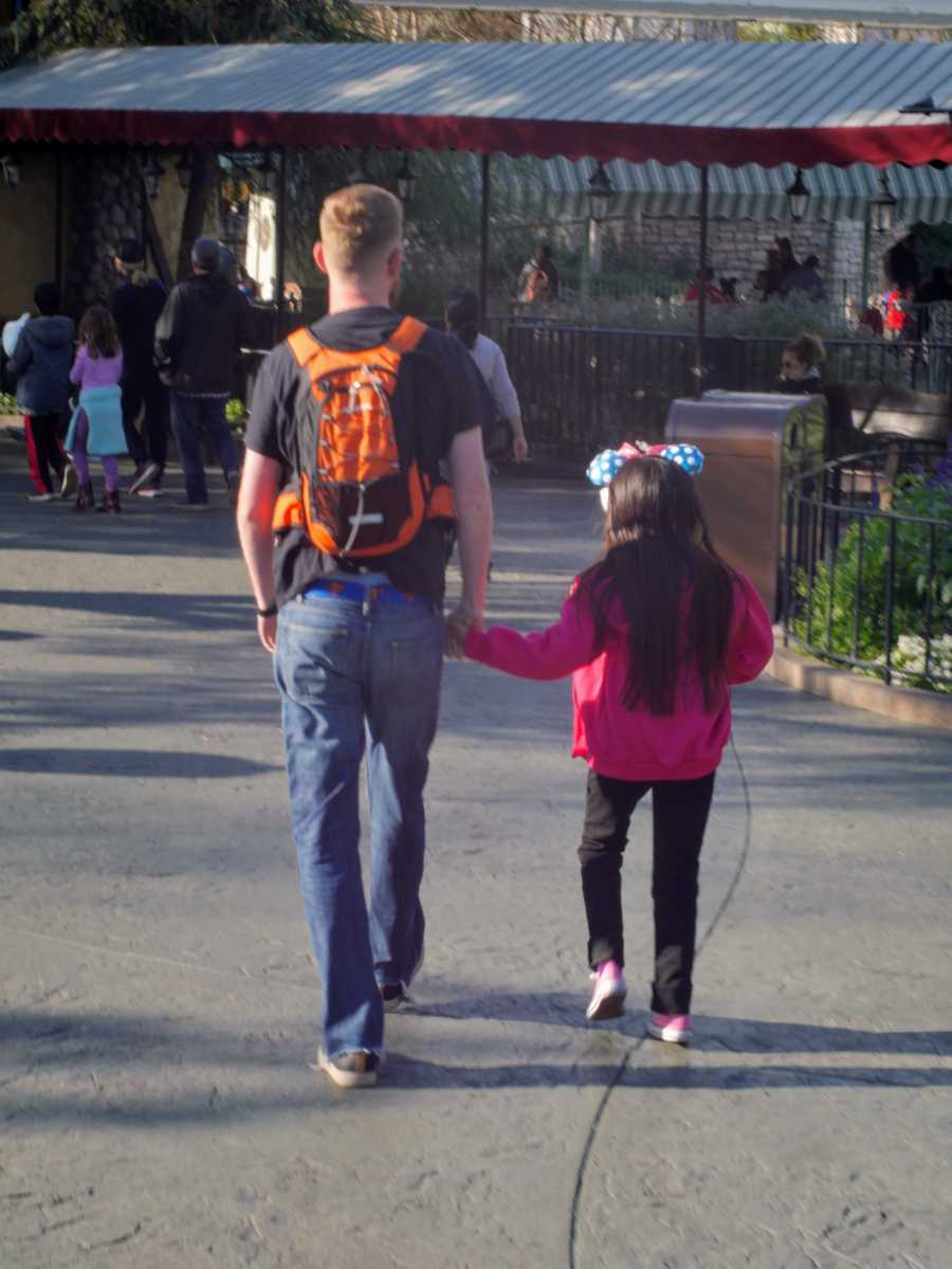 Father and daughter holding hands with backs to camera