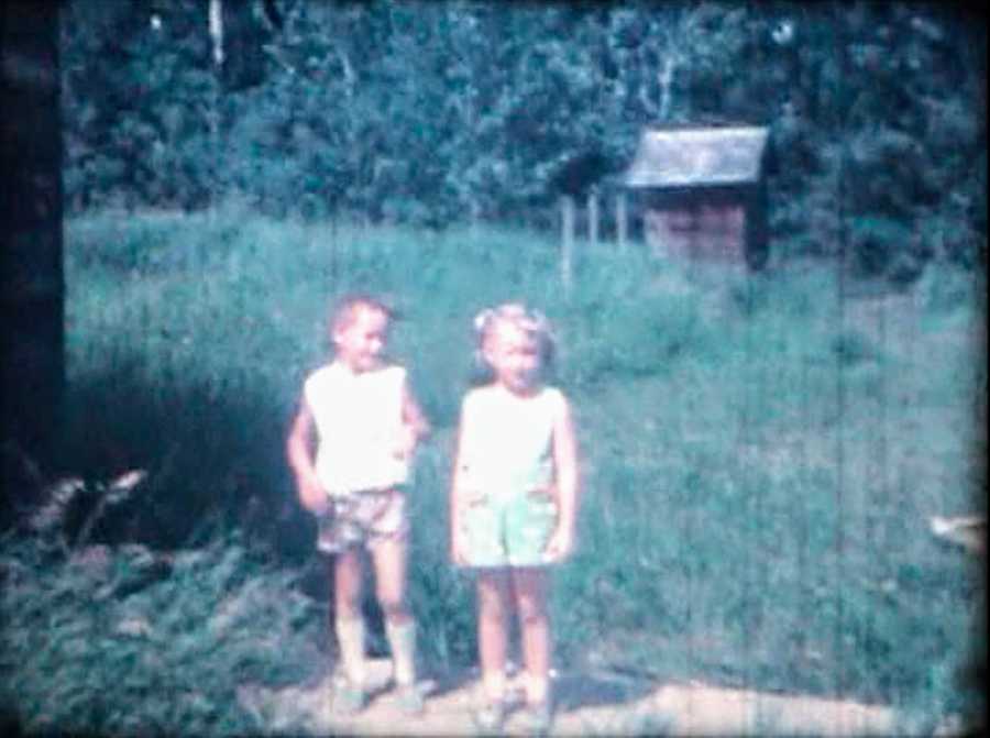 Old photo of two young girls standing outside in grass